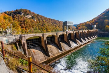 Majestic view of a dam spillway on the side of a mountain, with the tranquil waters of a lake below