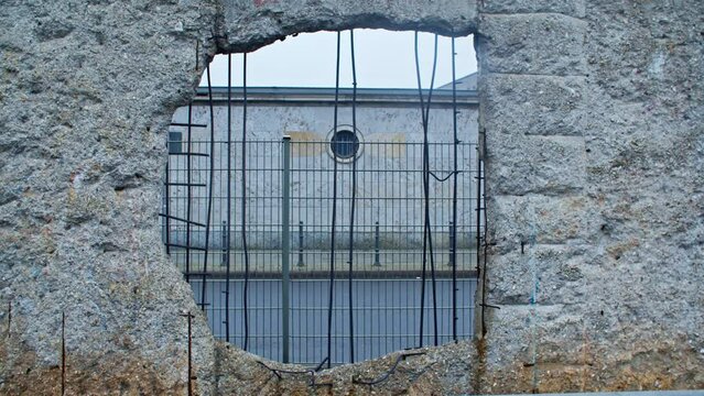 Remainings of Berlin Wall hole with car passing by in Baudenkmal Berliner Mauer