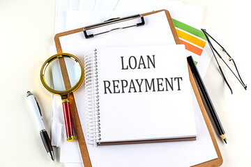 LOAN REPAYMENT text on notebook with clipboard on white background