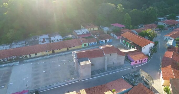 Sunset sunlight falls on church and seaside village with typical red roofs, aerial shot Chuao