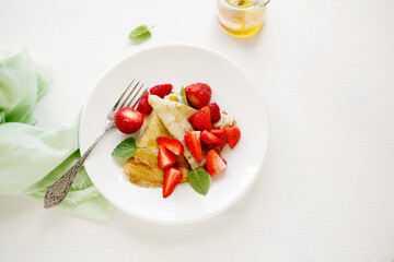crepes with fresh strawberries on light surface