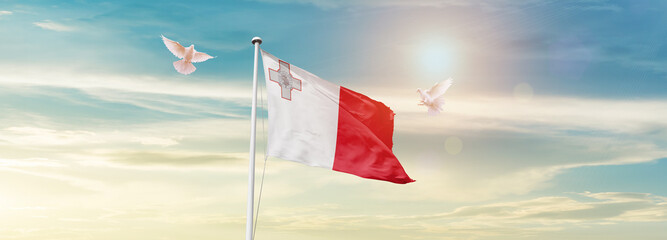 Waving Flag of Malta in Blue Sky. The symbol of the state on wavy cotton fabric.