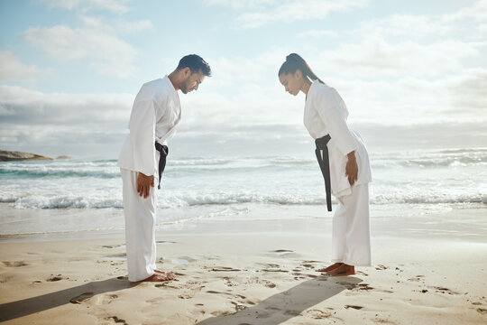 Beach, bow and people at karate training for exercise, sport and ready to start. Fitness, creative and an Asian man and woman at the ocean for martial arts, samurai fight and learning a skill