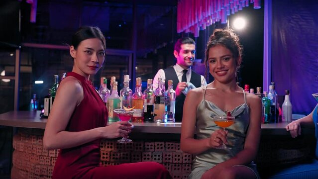 Beautiful asian women clink glasses and looking at camera and smile at bar restaurant