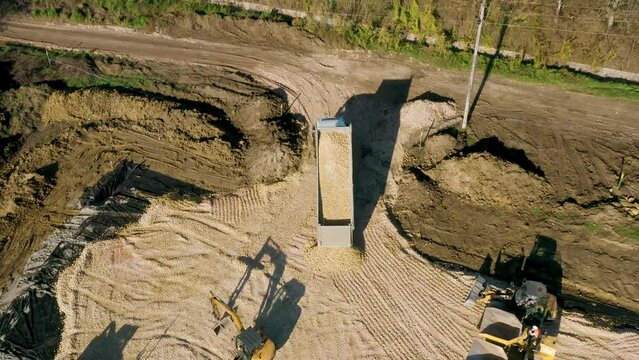 Aerial video of trucks on the street near a dug pit ready for a new building