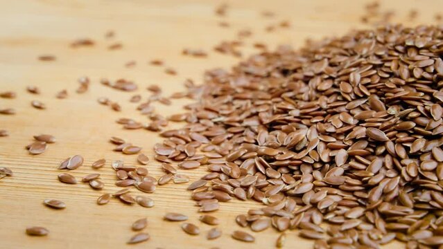 Closeup video of a handful of flaxseed on a wooden surface