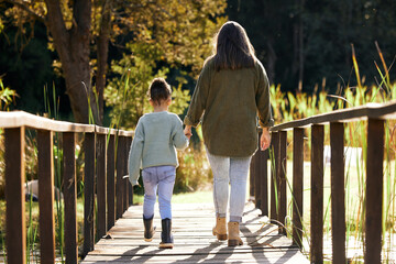 Back, mother and girl holding hands, park and bonding with love, family and carefree with sunshine....
