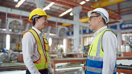 Two professional asian engineers men in safety uniform talking while standing at industry factory. Technician manager talking with new staff of factory