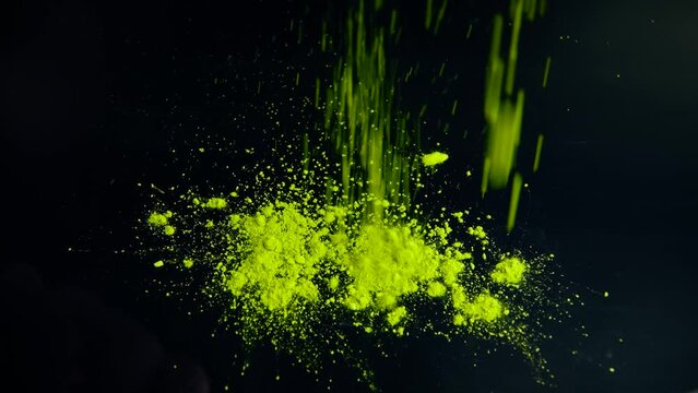 Close-up view of falling matcha tea powder on a black table