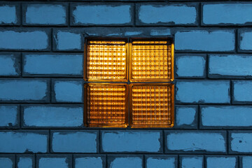 Glass block window in a white brick wall close up in the evening