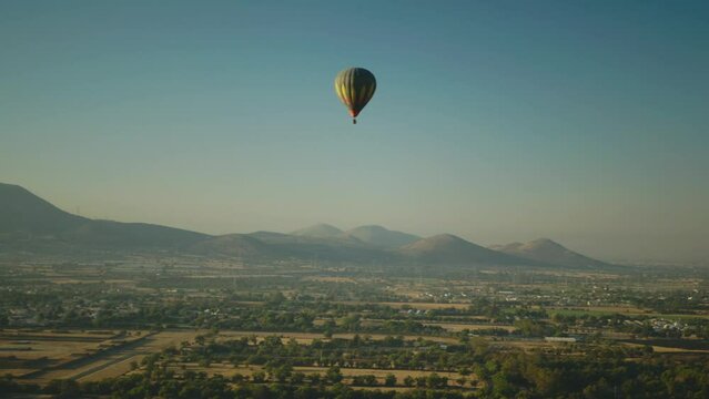 Single hot air balloon drifting over mountains and desert