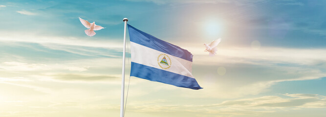 Waving Flag of Nicaragua in Blue Sky. The symbol of the state on wavy cotton fabric.