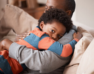 Love, portrait and boy hugging his father while relaxing on sofa in the living room of their home....