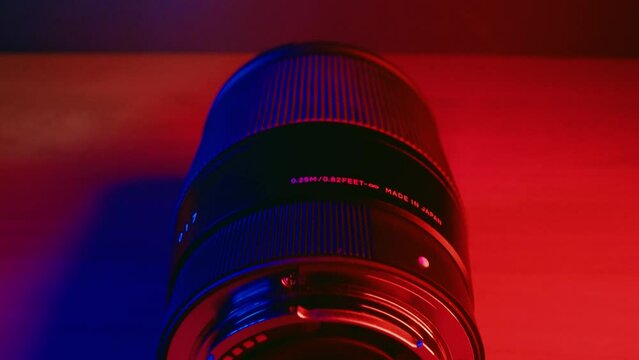 Professional camera lens on a table with red and blue lights in a room