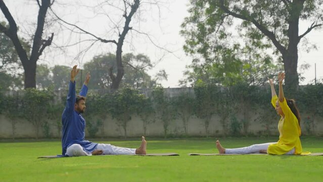 Indian couple doing head to knee yoga pose