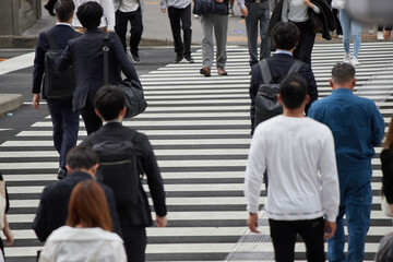 都内の交差点の横断歩道を渡る通勤中の人々の姿