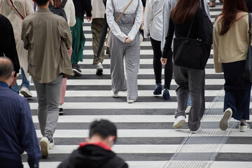都内の交差点の横断歩道を渡る通勤中の人々の姿
