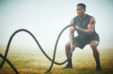Fitness, battle rope and man on field for power workout for body building, training and muscle...