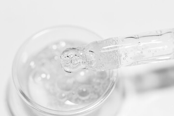 Transparent gel or liquid with bubbles in a round container. Pipette