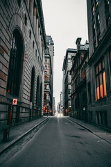 Fototapeta na wymiar Vertical shot of an empty street between old buildings in Montreal, Ontario, Canada on a gloomy day