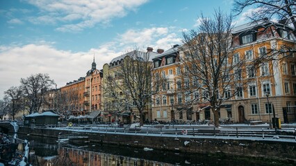 Naklejka premium Row of buildings by the channel and snowy trees in Uppsala, Sweden in winter