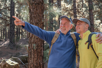 Happy and carefree couple of grandfather and grandson hiking together in the mountains in a...