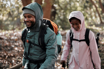 Happy, black couple and hiking with smile for travel, adventure or journey together in nature. African man and woman hiker walking or trekking in tree forrest or woods with backpack in the outdoors