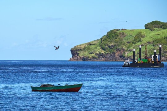 Beautiful Shot Of A Boat And An Industrial Ship Sailing On Bright Blue Water Under A Sunny Sky