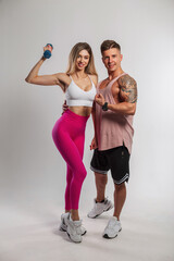 Beautiful fashionable sports couple posing on a white background. Beautiful fitness girl and handsome muscular man trainer in sportswear with sneakers in the studio