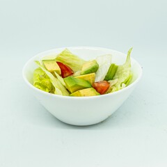 Bowl of salad with avocado, lettuce, and tomatoes on a white background
