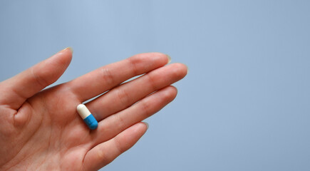 capsule on the palm of your hand on a blue background, medication, day of a medical worker, medical care, banner for the hospital