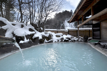 雪が積もる冬の露天風呂、白濁の温泉