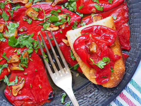 Close-up of Red Piquillo Pepper with garlic chips, parsley, hot pepper and antique fork