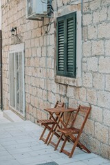 Fototapeta na wymiar Vertical shot of a stone wall of a house and a wooden folding table set in front of it