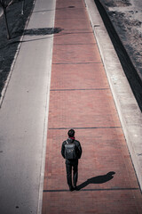 Vertical shot of a young man walking on the road
