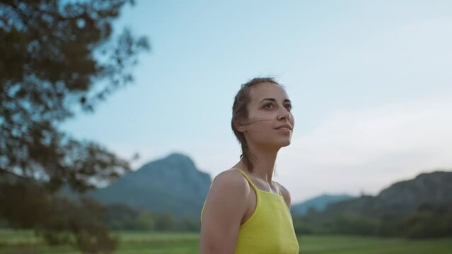 slow motion portrait of Young Athlete Woman enjoyinng beautiful green rural field landscape after running outdoors along Green Fields.