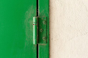 An old green hinge in a wall