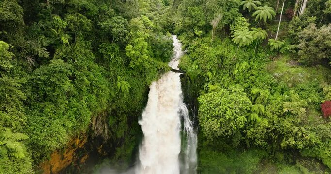 Aerial drone of Telun Berasap Falls in mountain jungle. Waterfall surrounded by green vegetation. Sumatra, Jambi, Indonesia.