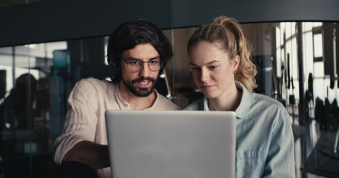 Close-Up Collaboration: Brunette Guy Explains to Blonde Woman by the Mirror Glass Wall in the Office