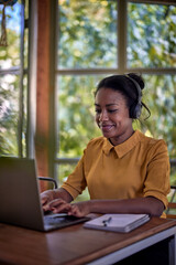Young businesswoman with headphones sitting in front of laptop and working from home.