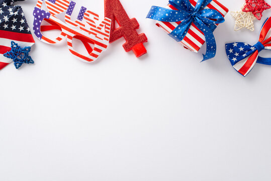 Celebration of USA's Independence Day with symbolic party accessories arranged from top view: rattan stars, number 4 candle, party eyeglasses, bow-tie, giftbox, white backdrop with space for text