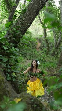 Hula dancer performing art and culture of hawaii connecting with nature in a personal wellness ritual in the middle of the trees.