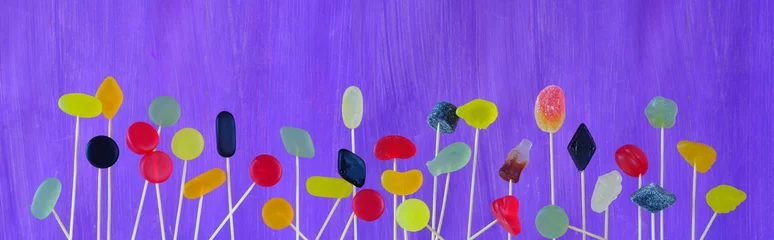 Fotobehang gummy candies, colorful jelly fruit gums, sweet food, close up, panoramic format on purple background.. © Kirsten Hinte