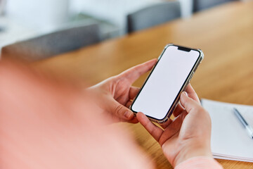 An adult woman holding a mobile phone with a blank white screen in her hands.