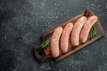 raw sausage for frying Grilled on cutting board with rosemary and spices. place for text, top view