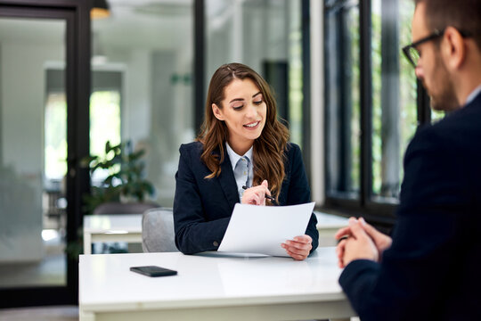 A businesswoman reading a cv of an ambitious man during the interview.