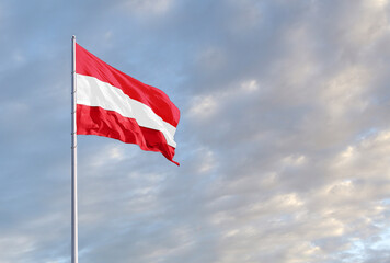 Waving Austrian flag against a blue sky with clouds and empty space for text. Room for text.