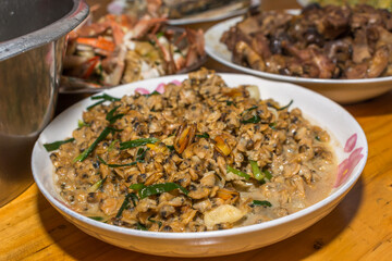 Close-up on cooked clams. Southern Chinese festivity rural food on bowls and plates at a wooden table.