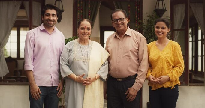 Portrait of Happy Indian Family Posing Together in Authentic Mumbai House. Senior Couple with Their Young Adult Children Looking at the Camera, Smiling While Taking a Family Photo. Zoom in Slow Motion