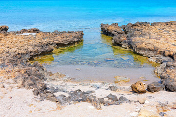 Fototapeta na wymiar Rocky sea lagoon with turquoise water . Sea shore with stones by summer